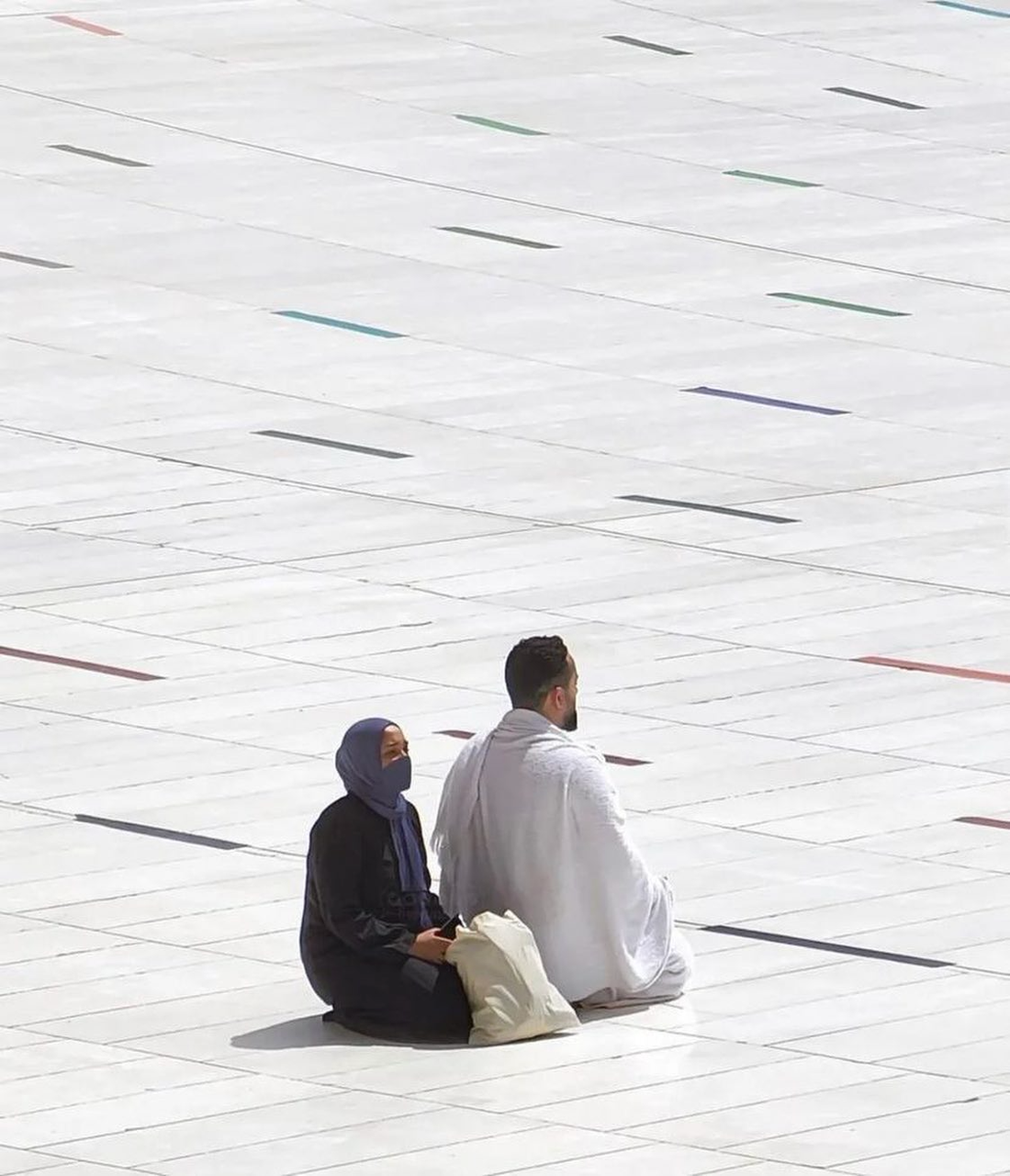 A WOMAN TAKES SHADE IN HER BROTHER'S SHADOW AT THE MASJID AL-HARAM, 2022